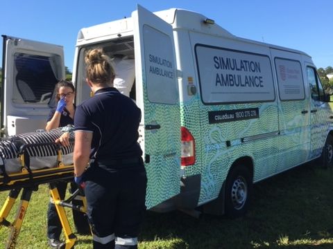 Students using ambulance simulation vehicle with Indigenous artwork